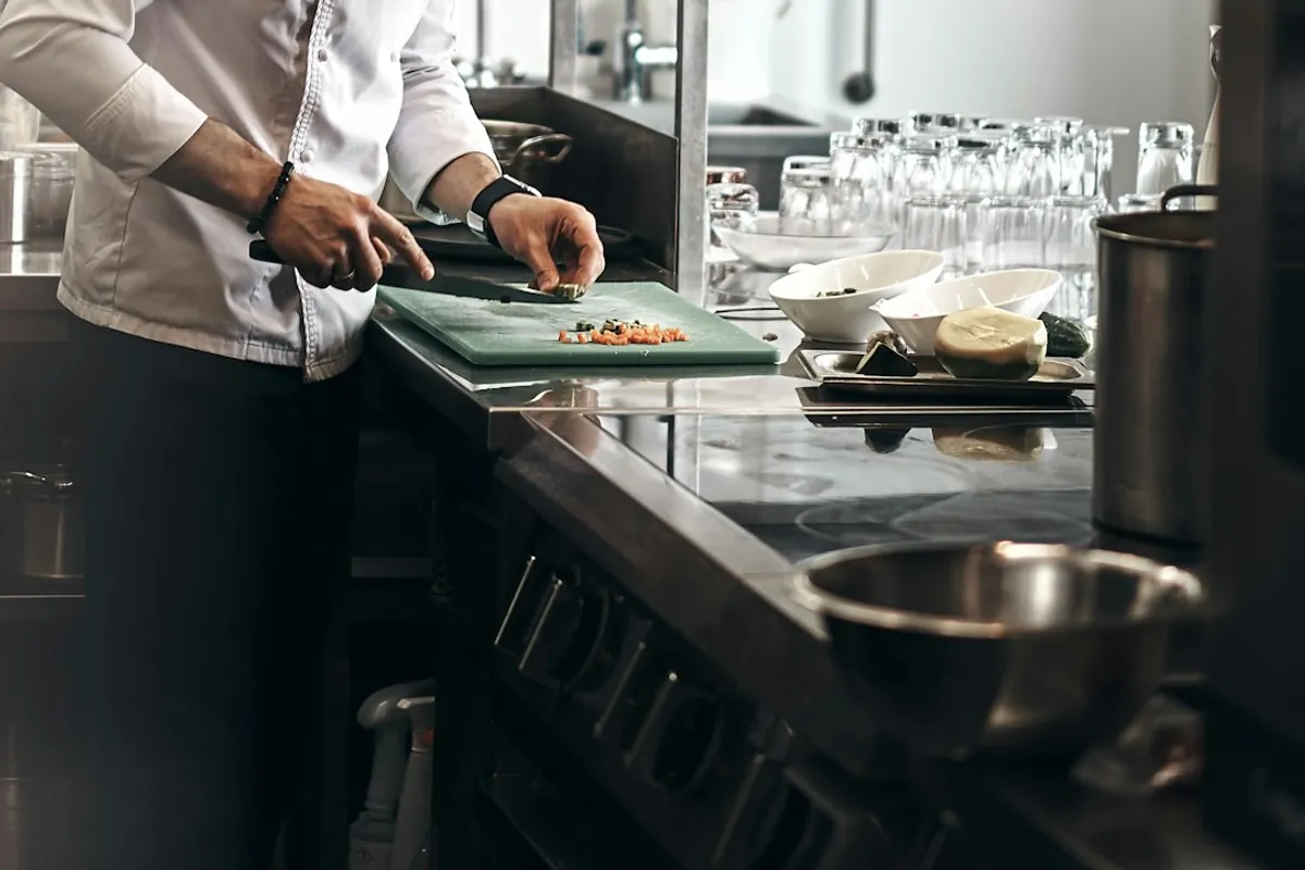 A chef chopping vegetables at a restaurant kitchen counter